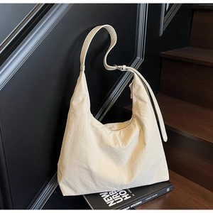Detail of a beige quilted nylon tote bag with adjustable strap and zipper closure