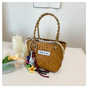 Close-up of woven straw handbag with inner drawstring pouch and decorative charms