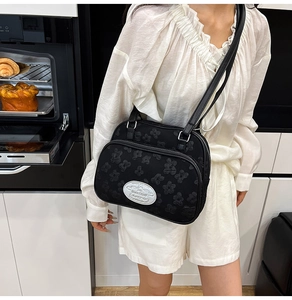 Détail d'un sac bandoulière noir gaufré avec plusieurs compartiments zippés sur un mannequin