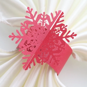 Macro detail of red laser-cut snowflake paper napkin ring on white fabric
