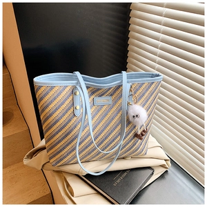 Détail du cabas tissé bleu et jaune avec anses en PU et breloque peluche monstre