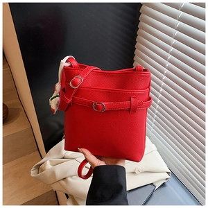 Détail du sac seau rouge à motif litchi avec boucle en métal et breloque ours