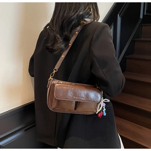 Detail view of vintage brown crossbody bag with gold hardware and fashion charms