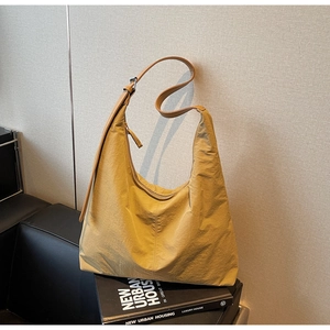 Close-up of mustard yellow hobo bag with nylon crinkle texture on black leather seat