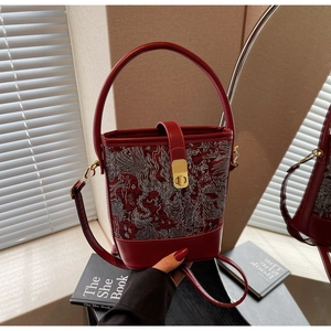 Close-up of vintage wine red bucket bag with traditional phoenix embroidery and gold lock