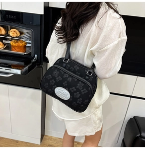 Détail du sac sous l'aisselle noir avec texture florale 3D et logo argenté