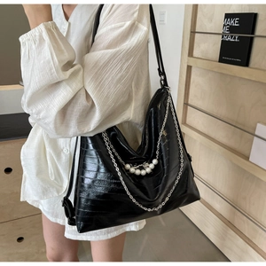 Makroansicht der schwarzen Hobo-Tasche aus Kroko-Lackleder mit Perlen und Kettenverzierung