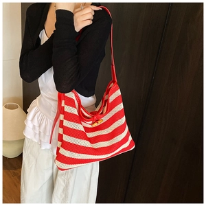 Detail of red and white striped woven tote bag featuring a natural bamboo clasp and leather strap