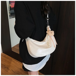 Detail of white crocodile pattern hobo bag with cute plush bear charm on the strap