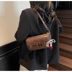 Detail of dark brown leather pillow bag with pearl heart charm and gold hardware accents
