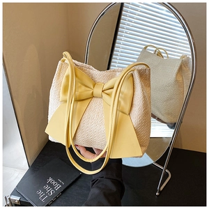 Détail du sac fourre-tout tissé beige avec nœud jaune et ses lanières assorties