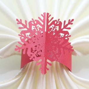 Close-up of red laser-cut snowflake napkin ring on elegant white fabric
