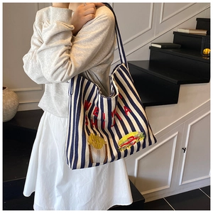 Détail du sac cabas rayé en toile avec broderie burger et anses bleues robustes