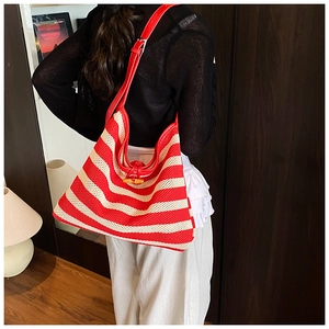 Detail of red and white striped woven tote bag with leather strap and wooden horn buckle