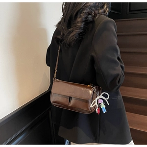 Detail of vintage brown patent leather shoulder bag with fashion embossing and charms
