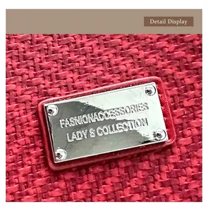 Detailed close-up of polished silver hardware plate on a red tweed tote bag