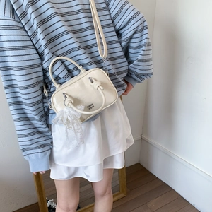 Detail der cremeweißen Boston-Tasche mit Spitzenschleife und weichem Glanzfinish