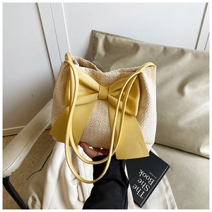 Détail du sac seau en paille avec un grand nœud jaune et des textures tressées