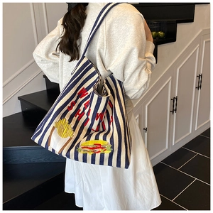 Détail du sac cabas en toile rayé bleu avec broderies de burger et frites colorées
