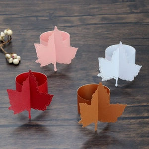 Detail view of laser-cut maple leaf paper napkin rings in red, pink, white, and gold colors