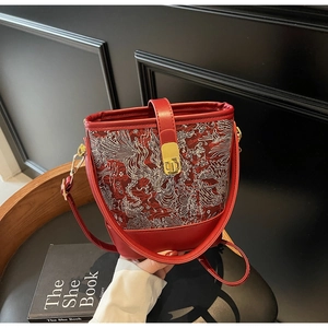 Detailed view of red bucket bag with white embroidery and golden metallic clasp