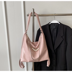 Detail der rosa Hobo-Tasche in Krokoprägung mit Silberkette und Perlen-Bogen-Anhänger
