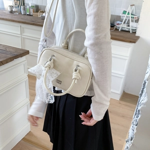 Detailansicht der cremefarbenen Handtasche mit Spitzenbesatz und Schultergurt