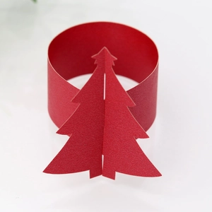 Détail d'un rond de serviette en papier rouge avec motif sapin de Noël découpé au laser