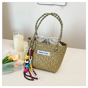Detail of woven straw tote bag with beaded tassel and drawstring liner for beach use