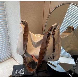Detailaufnahme der beigen Canvas-Hobo-Tasche mit braunem Lederriemen und TCT-Schriftzug