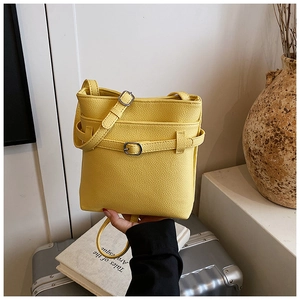 Détail du sac seau jaune en cuir grainé avec boucle décorative et bandoulière