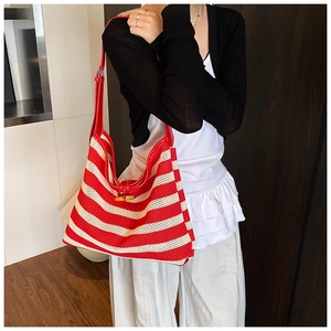 Detail of red and white woven hobo bag with red leather strap and horn toggle closure