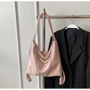 Detail von rosa Kroko-Leder mit Perlen-Schleife und silberner Kette an der Tasche
