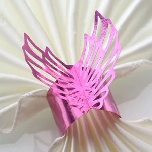 Detailed close-up of pink glitter laser-cut butterfly napkin ring on a white silk napkin