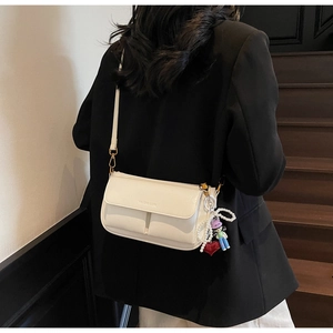 Detail of cream white pillow bag with pearl charm and red heart on black blazer outfit