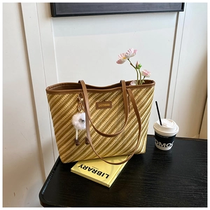 Détail de la texture tressée et du bord en cuir marron du grand sac cabas en paille