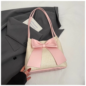 Vue détaillée du sac seau en paille crème avec grand nœud rose et bandoulière rose