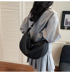 Detail of black pebbled leather crescent bag featuring a textured finish and strap