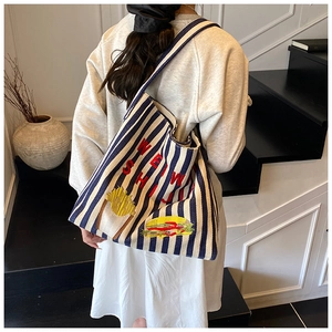 Détail du sac cabas en toile à rayures bleues avec motifs brodés et texte élégant