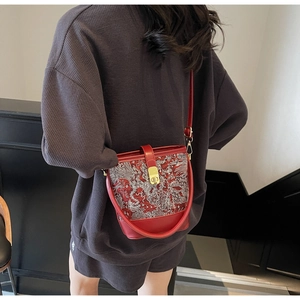 Detail of red water bucket bag featuring traditional white dragon embroidery and gold lock