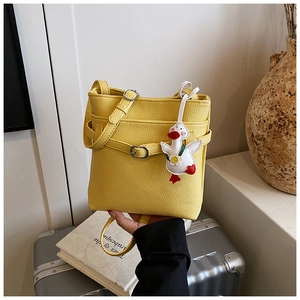 Détail du sac seau jaune à texture litchi avec un adorable pendentif canard blanc