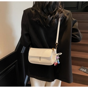 Detail of white PU leather shoulder bag with logo embossing and colorful cute charms