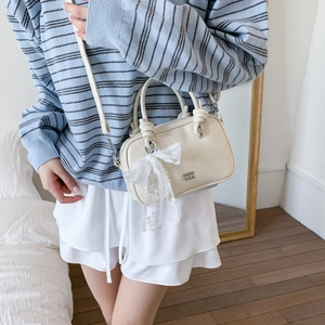 Detailansicht der cremefarbenen Ledertasche mit Spitzen-Schleife und Knotengriff-Design