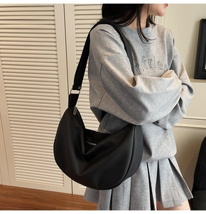 Detail view of black textured leather crescent bag with adjustable wide shoulder strap