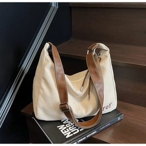 Detail der Vintage-Canvas-Hobo-Tasche mit Lederriemen und TCT-Logo auf dunklem Grund