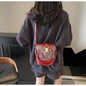 Macro detail of red leather bucket bag with traditional silver dragon embroidery
