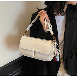 Detail of white leather shoulder bag with YA SHI LUN logo and cute doll pendant