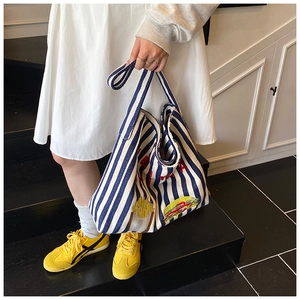 Vue détaillée du sac cabas en toile rayée bleue avec broderie rouge et motif soleil