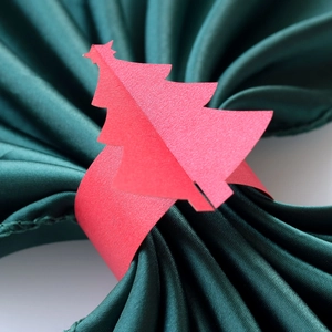 Gros plan d'un rond de serviette en papier sapin de Noël rouge sur du satin vert