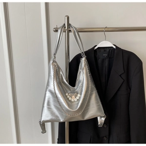 Detail der silbernen Metallic-Hobo-Tasche mit Perlenbogen und Metallkette